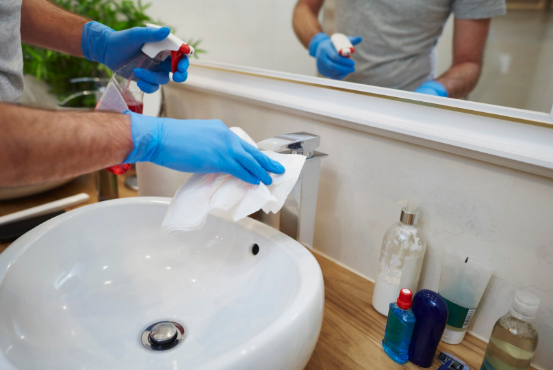 Man's hands cleaning sink in the bathroom