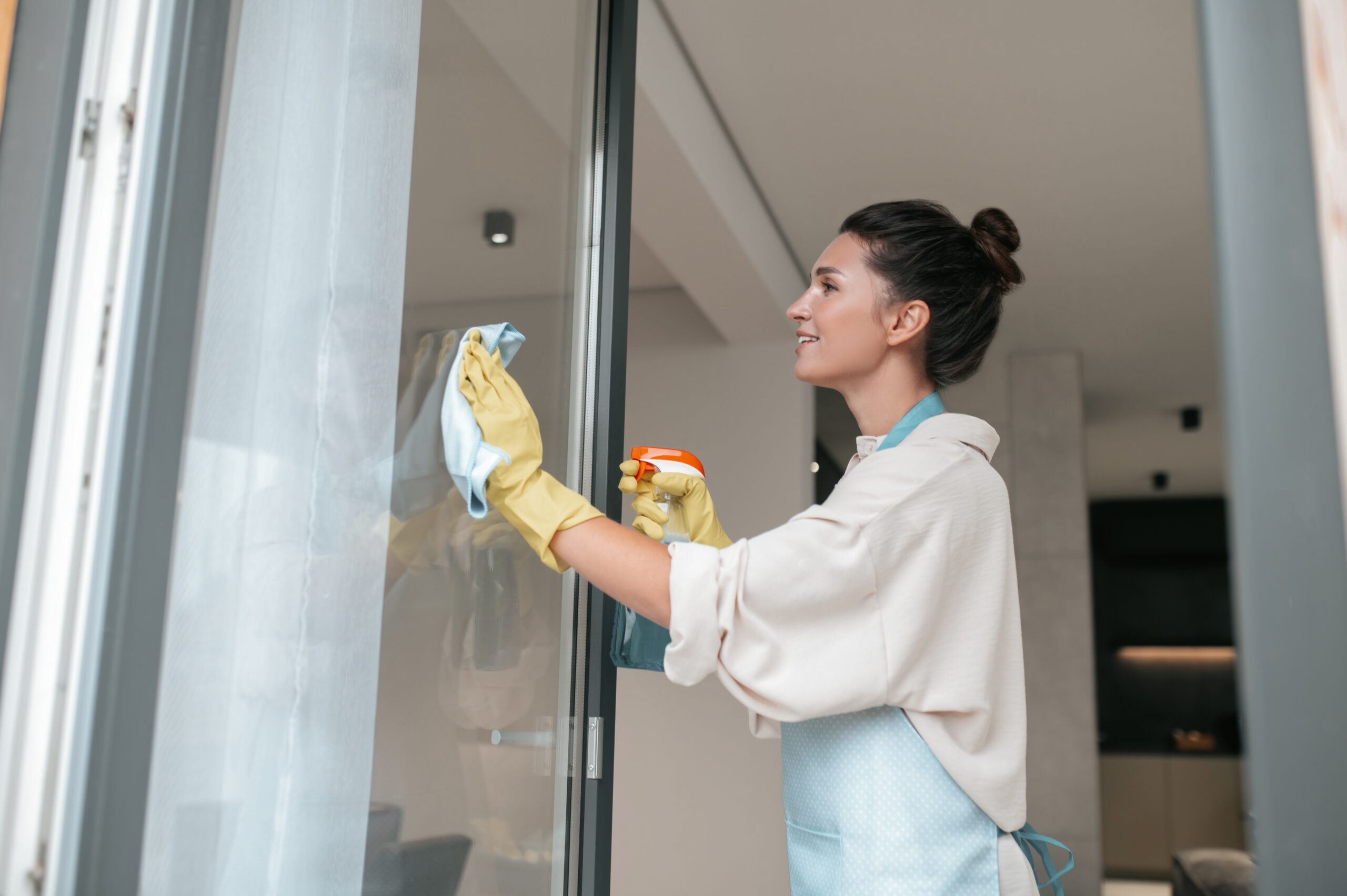 A woman in apron cleaning the windows