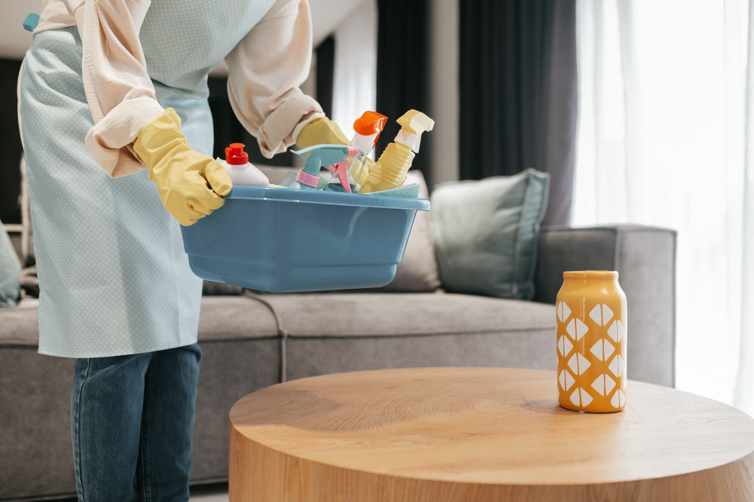 Dark-haired woman carrying a basin with disinfection supplies