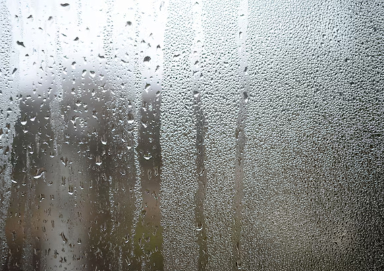 A photo of the glass surface of the window, covered with a multitude of droplets of various sizes.