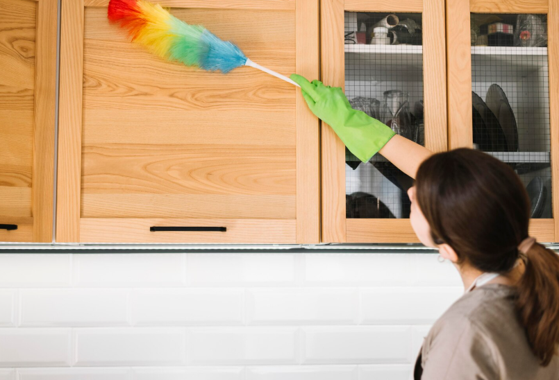 Woman using colorful fluffy duster while dusting