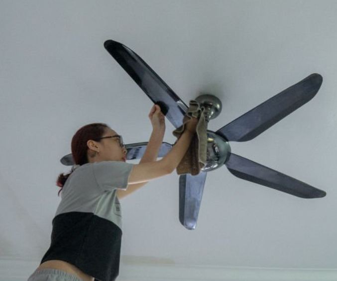 woman cleaning a ceiling fan